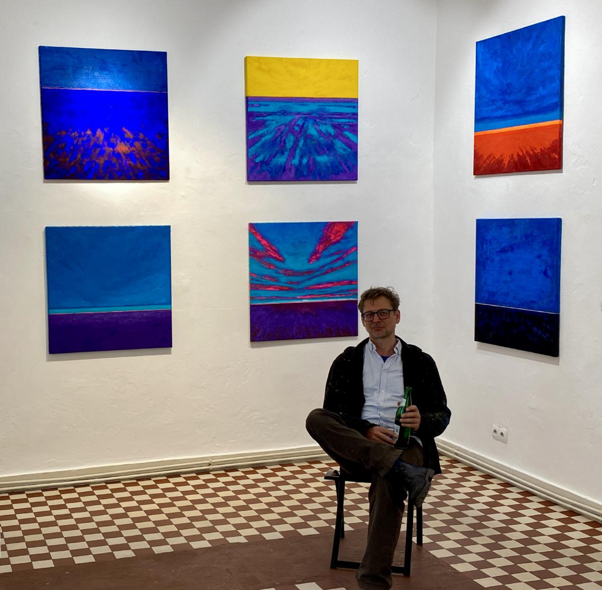 Bernd David vor einer Reihe mit sechs Gemälden der Reihe Infinity Fields